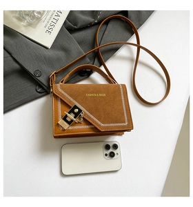 Détail du sac bandoulière bicolore marron avec finition en daim et surpiqûres élégantes