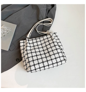 Close-up of black and white tweed tote bag with fine white leather shoulder straps