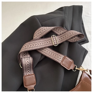 Close-up of adjustable wide woven shoulder strap with retro chevron pattern and gold hooks