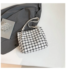 Detail of tweed checkerboard shoulder bag with cream leather strap on neutral background