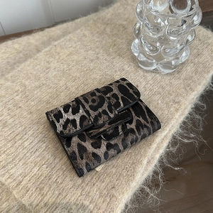 Mini leopard print square wallet with button closure on beige knitted blanket background