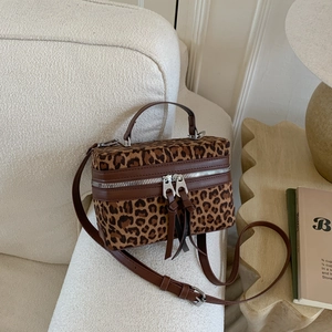 Sac bandoulière rétro à motif léopard avec détails en cuir marron sur un canapé blanc