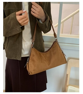 Brown suede underarm bag with sleek leather strap shown in a cozy indoor lifestyle scene