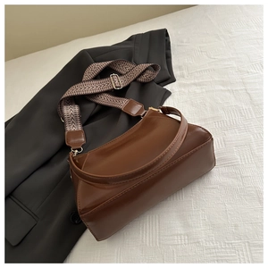 Close-up of brown leather tote bag featuring stylish zigzag woven adjustable shoulder strap
