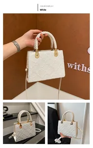 Detail of white mini square bag showing woven handle, gold hardware and embossed texture