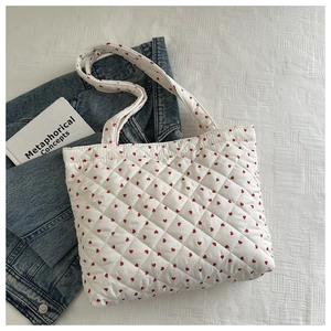 Borsa tote bianca trapuntata con cuori rossi su giacca di jeans e sfondo in tessuto