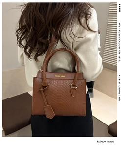 Detail of a brown crocodile pattern handbag featuring luxury textures and top handles