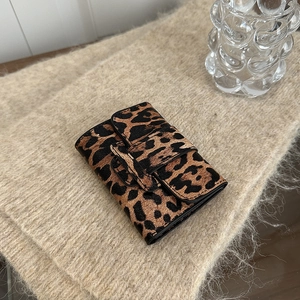 Mini leopard print trifold wallet with faux calf hair texture on a beige knit background