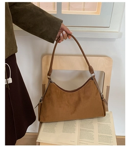 Détail d'un sac hobo en daim marron avec surpiqûres blanches et fines poignées