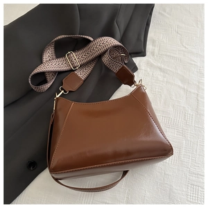 Detail of brown faux leather crossbody bag with chic herringbone pattern woven strap