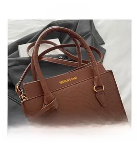Detail of brown crocodile pattern leather handbag with gold embossed logo text