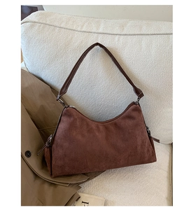 Gros plan d'un sac hobo en daim marron avec surpiqûres décoratives sur un canapé texturé