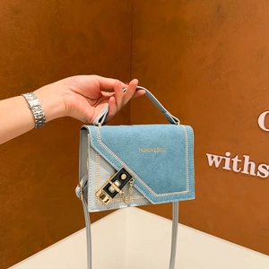 Sac bandoulière bleu texture denim avec boucle métallique et chaîne sur fond brun élégant
