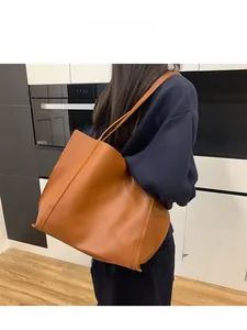 Detail view of large brown faux leather tote bag with stitching on slim shoulder straps