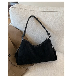 Vue détaillée d'un sac hobo en daim noir avec coutures blanches contrastées sur un canapé