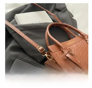 Detail of brown crocodile pattern handbag with gold buckle and adjustable strap