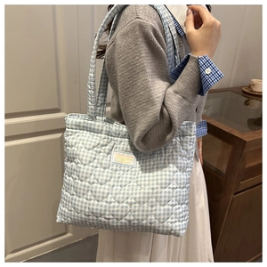 Detalle de bolso tote de cuadros con acolchado de corazones y etiqueta de marca suave