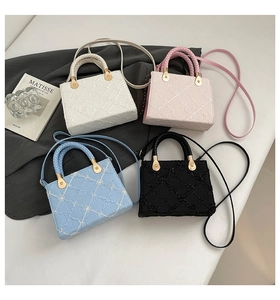 Close-up of quilted square handbags in white, pink, blue, and black with woven handles