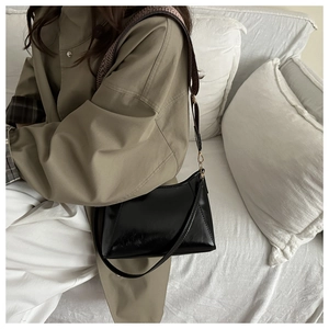 Close-up of black geometric tote bag with wide woven strap on white sofa