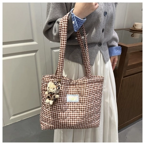 Detalle de pespuntes de corazón en bolso tote de cuadros marrones con colgante gato