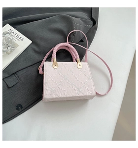 Detail of light pink crossbody bag with embossed diamond texture and woven handle