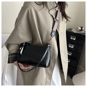 Detail of black PU leather pillow bag featuring a wide ethnic style woven shoulder strap