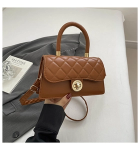 Detail of brown quilted faux leather handbag with golden twist lock and round handle