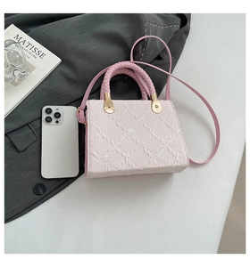 Detail of light pink floral jacquard fabric and woven handle on a small square handbag