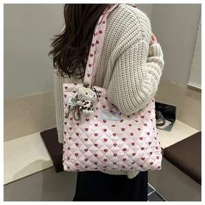 Dettaglio della borsa tote trapuntata rosa con cuori e un ciondolo di peluche