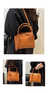 Detail of brown faux leather handbag with embossed snakeskin texture and gold lettering