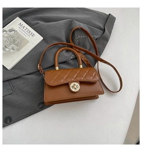 Detail of brown quilted texture and gold metal buckle on a retro square shoulder bag