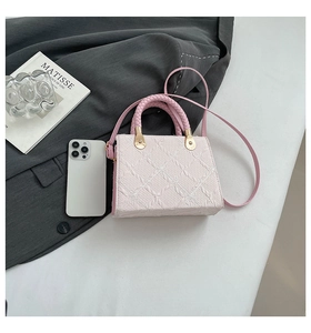 Macro view of light pink square handbag with 3D floral texture and woven handle detail
