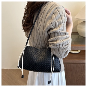 Dettaglio di una borsa hobo intrecciata nera con coulisse bianca indossata da modella