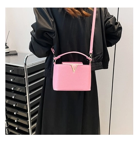 Pink crossbody bag with gold V-letter metal logo and elegant leather texture