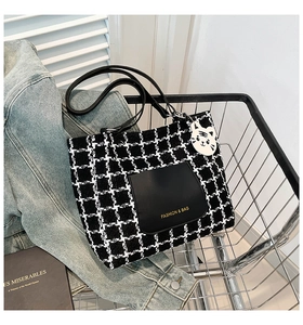 Checkered fabric tote bag with black leather pocket and cute white cat charm in a cart