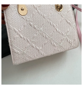 Detail of pink quilted handbag featuring bow embroidery and gold metallic clasp