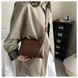 Détail d'un sac cabas en cuir marron avec bandoulière tissée amovible au motif rétro