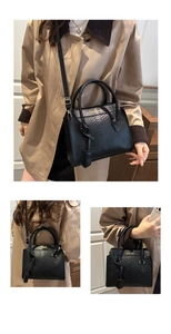 Detail of black faux snake pattern embossing with gold logo on classic handbag