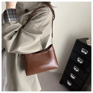 Detailed side view of a brown vintage faux leather shoulder bag with sleek trapezoid structure