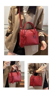 Detail of red faux crocodile leather handbag with golden logo and adjustable strap