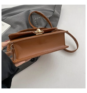 Detail of caramel leather texture and golden metal twist lock on the crossbody bag