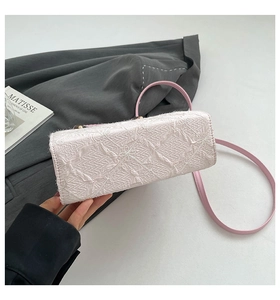 Detailed close-up of textured pink square bag with geometric embroidery and tassel accents
