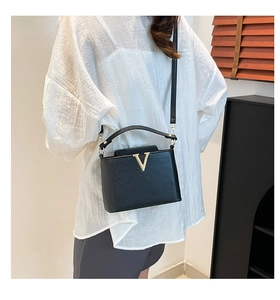 Close-up of black crossbody bucket bag with golden V hardware and leather texture