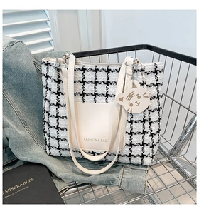 Macro detail of black and white tweed tote bag with leather pocket and cat charm