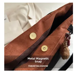 Gros plan du fermoir magnétique doré et de la texture en daim marron du sac à main