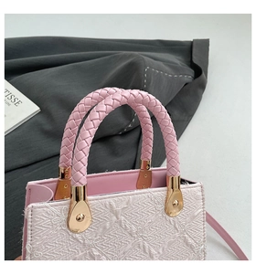 Detail of pink lace handbag with woven leather handle and gold-tone teardrop hardware