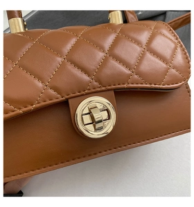 Detailed macro view of caramel brown quilted PU leather handbag with gold twist lock