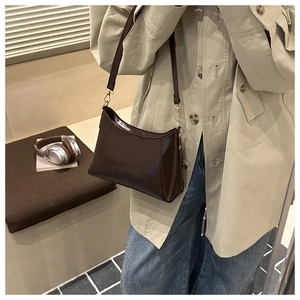Close-up of a vintage dark brown leather tote bag with elegant gold metal hardware