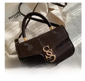 Detail of dark brown faux snake-skin texture flap and golden S-shaped metal lock