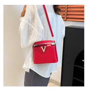 Close-up of red pebbled leather bucket bag with a stylish gold V-shaped metal buckle detail